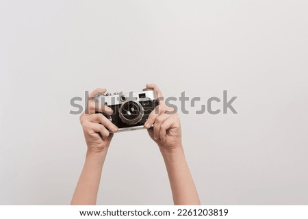 Raised hands of a photographer holding a retro camera