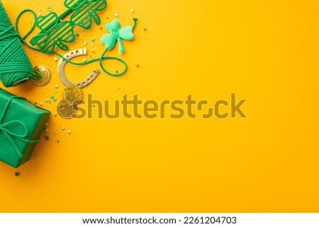 Saint Patrick's Day concept. Top view photo of giftbox gold coins clover shaped party glasses shamrocks horseshoe spool of twine and sprinkles on isolated yellow background with empty space