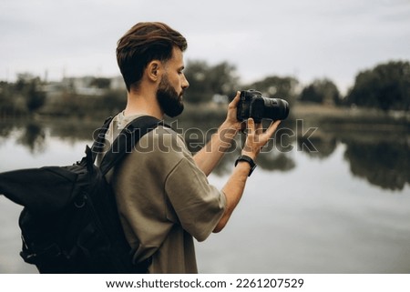 a young man with a modern SLR camera in his hands on a natural background