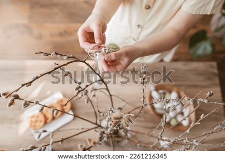 Close-up of a girl's hands hanging a decorative Easter egg on a willow branch at home. Decorating your home for Easter Royalty-Free Stock Photo #2261216345