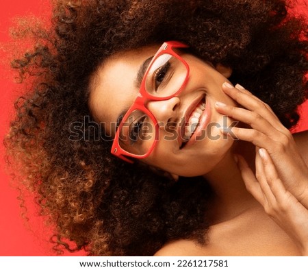 Happy woman wearing eyeglasses smiling, has good mood isolated on studio red background. Excited african american female. Positive life concept. Royalty-Free Stock Photo #2261217581