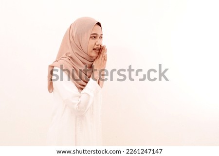 Portrait of young asian muslim woman with whispering or telling secret gesture. Ramadhan concept.
