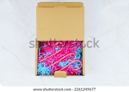 Small cardboard box open top view with Umbrella shape sugar cane, colourful corrugated cardboard paper pieces instead bubble wrap in big cardboard box delivered parcel. Zero waste, recycle, gift.