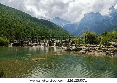 Beautiful lake and waterfall at Blue Moon Valley with background of Jade dragon snow mountain in Lijiang, Yunnan, China. Defocus picture.