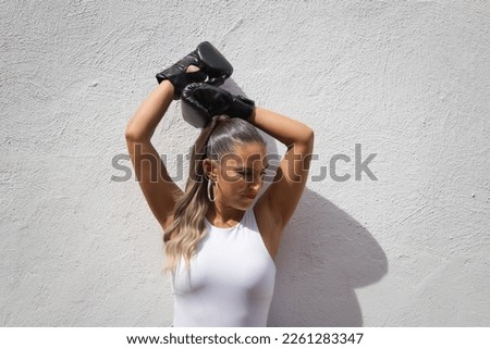 Cute young woman with boxing gloves and white top makes different gestures and expressions on white background. Woman is having fun. Concept claims.