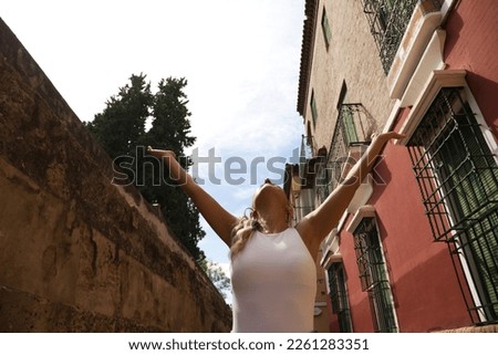 Young woman raises her arms to the blue sky. Concept of freedom and success and relaxation. The photo is taken from below.