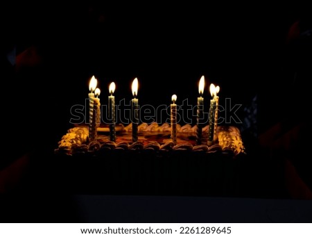 On a dark background a cake with burning candles. Birthday background. Holiday. Celebrate birthday. Children's holiday.