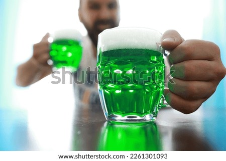 Saint Patrick's Day holiday. National Irish holiday. Green beer. Hand with a mug emerald beer in a bar.