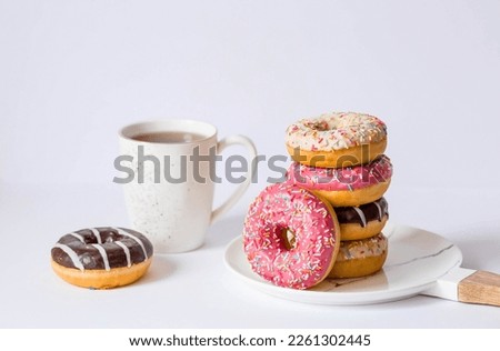 Delicious dessert. Pink, white and chocolate donuts with multicolored sprinkles, a cup of black coffee or tea. Sweets. Royalty-Free Stock Photo #2261302445