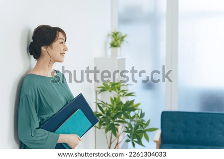 Middle aged Asian woman standing in casual office.