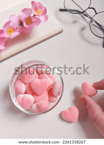 Pink and white gummy hearts with strawberry flavored. Served on transparent glass. Sweet taste. Isolated background in white