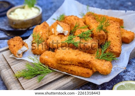 Close up of   Crispy breaded  deep fried allasca polloc fish fingers with breadcrumbs served  with remoulade sauce and  lemon Cod Fish Nuggets on rustic wood table background