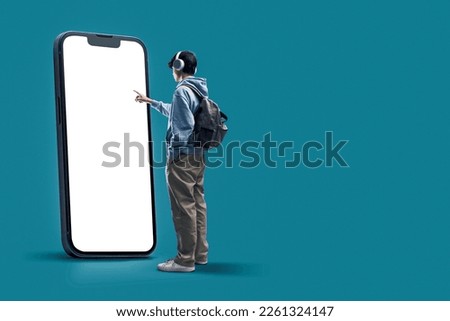 Student interacting with a big touch screen smartphone with blank display, online learning and mobile apps concept, copy space Royalty-Free Stock Photo #2261324147