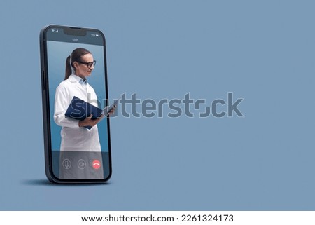 Professional doctor in a smartphone videocall and checking medical records, online doctor and telemedicine concept Royalty-Free Stock Photo #2261324173