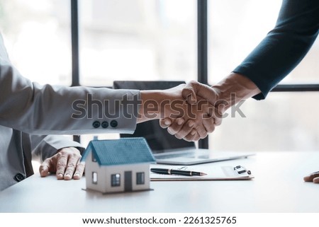 Real estate agent shakes hands with a client to sign a home purchase contract congratulating the client on the purchase. Royalty-Free Stock Photo #2261325765