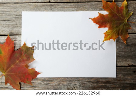 White sheet with autumn leaves on grey wooden background