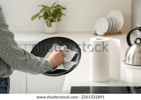 Woman wiping frying pan with paper towel in kitchen, closeup Royalty-Free Stock Photo #2261332891