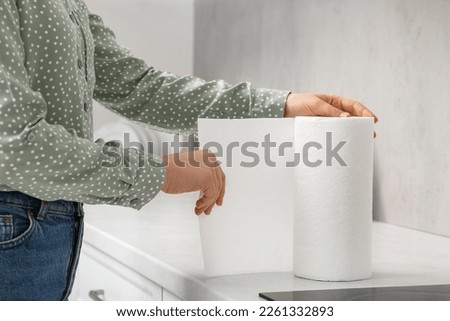 Woman tearing paper towels in kitchen, closeup Royalty-Free Stock Photo #2261332893