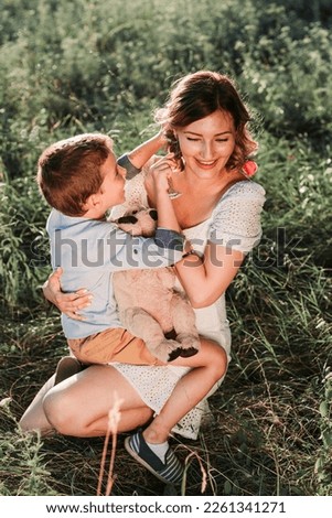 Cute blond boy putting flower behind moms ear. Mothers day