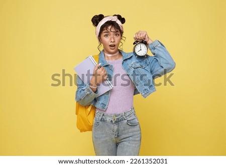 young asian woman student hold books look at clock isolated on yellow background. student go to school late time. 