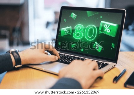 Close up of hands using laptop with green 80% sale hologram. Online shopping and money concept