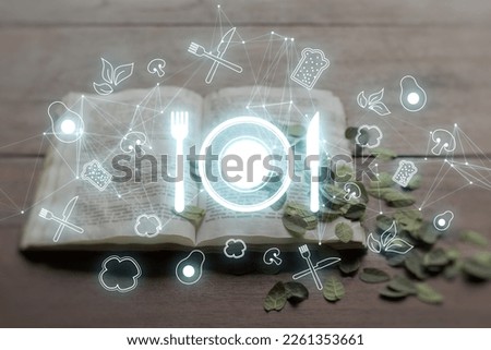 Futuristic restaurant menu application concept with glowing silverware hologram on blurry background. Close up of cookbook with dried leaves on blurry background. Double exposure