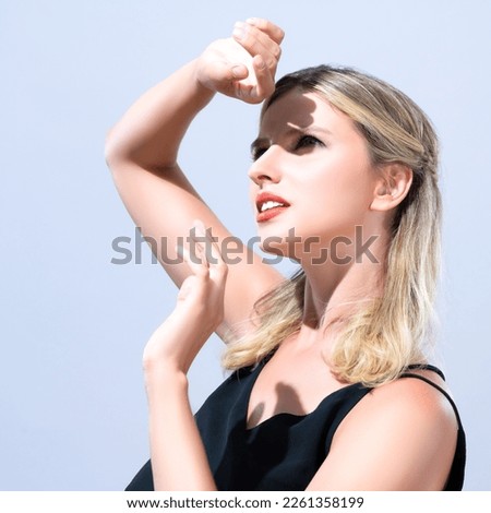 Closeup young blond hair woman with perfect skin and soft alluring facial makeup raise her hand cover her face from bright sunlight in isolated background for skincare sunscreen product. Royalty-Free Stock Photo #2261358199