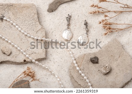 Beautiful Pearl Jewelry on white stones and sand. Necklace and earrings made of silver