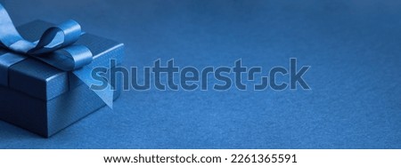 Part of Luxury gift box with a blue bow on blue. side view monochrome. Fathers day or Valentines day gift for him. Corporate gift concept or birthday party. Festive sale wide banner Royalty-Free Stock Photo #2261365591