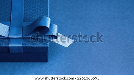 Luxury gift box with a blue bow on blue. High angle view monochrome close up. Fathers day or Valentines day gift for him. Corporate gift concept or birthday party. Festive sale Royalty-Free Stock Photo #2261365595