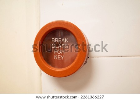 A red colored emergency break glass panel in case of a fire emergency. It is installed in all buildings