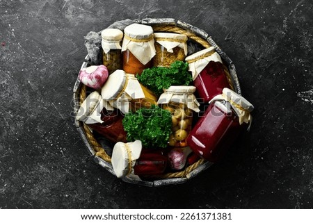 Wooden box with food supplies. Marinated vegetables. Food stocks in case of crisis. On a stone background. Top view.