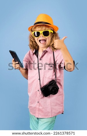 Cute child takes picture with camera and phone. Traveller kid boy chatting on phone. Vacation travel lifestyle. Travel and tourism concept.