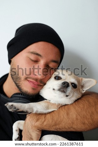 stylish guy, teenager, dressed in black clothes, black hat. the guy is at home with his chihuahua dog, friends hugging, playing, spending time together, the dog is the guy's best friend. comfortable h