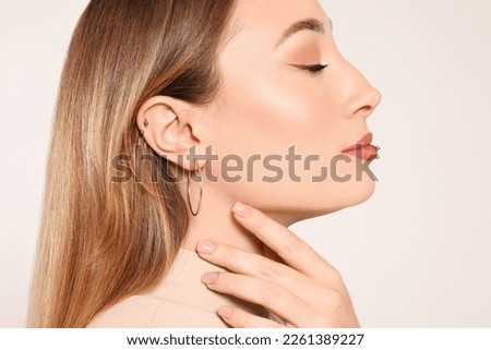 Young woman with lip and ear piercings on white background, closeup