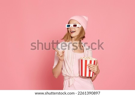 woman in t-shirt and hat with popcorn pointing at the copy space