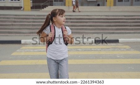 girl child goes through pedestrian crossing. happy student with school backpack. zebra road. child girl crosses road zebra. pedestrian traffic sign. road rules. girl child goes from lessons classroom.