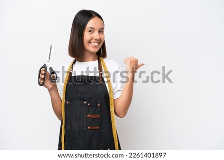 Young seamstress woman isolated on white background pointing to the side to present a product Royalty-Free Stock Photo #2261401897