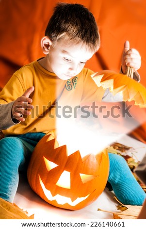 A cute photograph of a boy and her lighting Halloween pumpkin