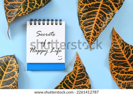 Secrets of a happy life motivational and inspirational guide written on blue notepad. Beautiful flat lay composition.