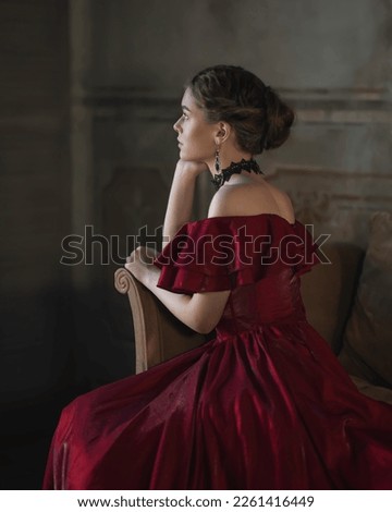 Aristocratic girl in a red dress in profile Royalty-Free Stock Photo #2261416449