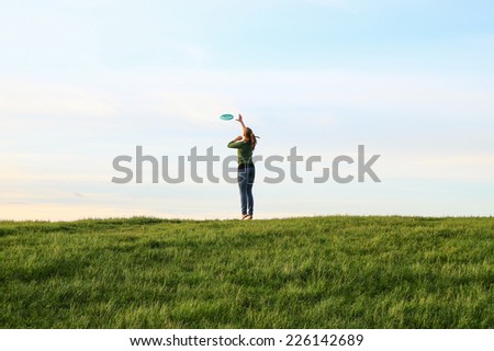A young woman playing with a frisbee in a park.