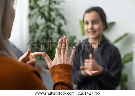 Small Caucasian teen girl child do articulation exercises with caring mother or teacher at home. Little kid pronounce sounds speak talk with tutor or coach, engaged in voice pronunciation together Royalty-Free Stock Photo #2261427969