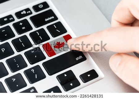 Computer key with the Canada on it. Male hand pressing computer key with Canada flag.