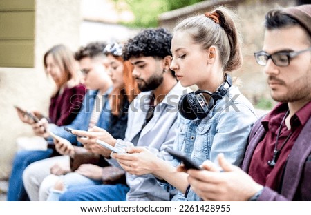 Side view of milenial men and women using smartphone devices - People addicted by mobile phone - Tech life style concept with always connected teenagers - Bright filter with focus on first right woman Royalty-Free Stock Photo #2261428955