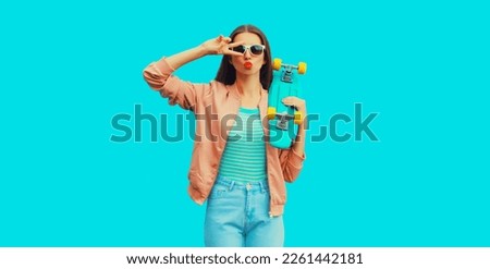 Portrait of cheerful young woman with skateboard on blue background