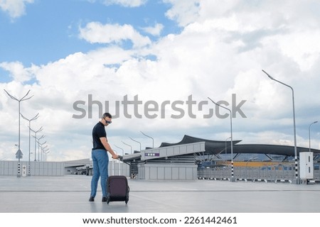 Young man with luggage in an empty airport parking lot. People lifestyles and transportation concept