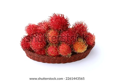 Rambutan or hairy fruits served on rattan plate isolated on white background