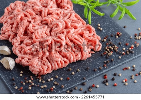 Fresh raw minced pork and spices in a on a cutting board close up on a grey table
