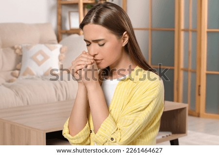 Woman with clasped hands praying at home Royalty-Free Stock Photo #2261464627